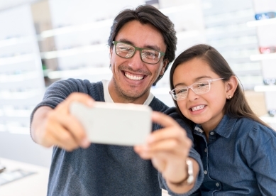 Father and daughter taking selfie in eye glass store